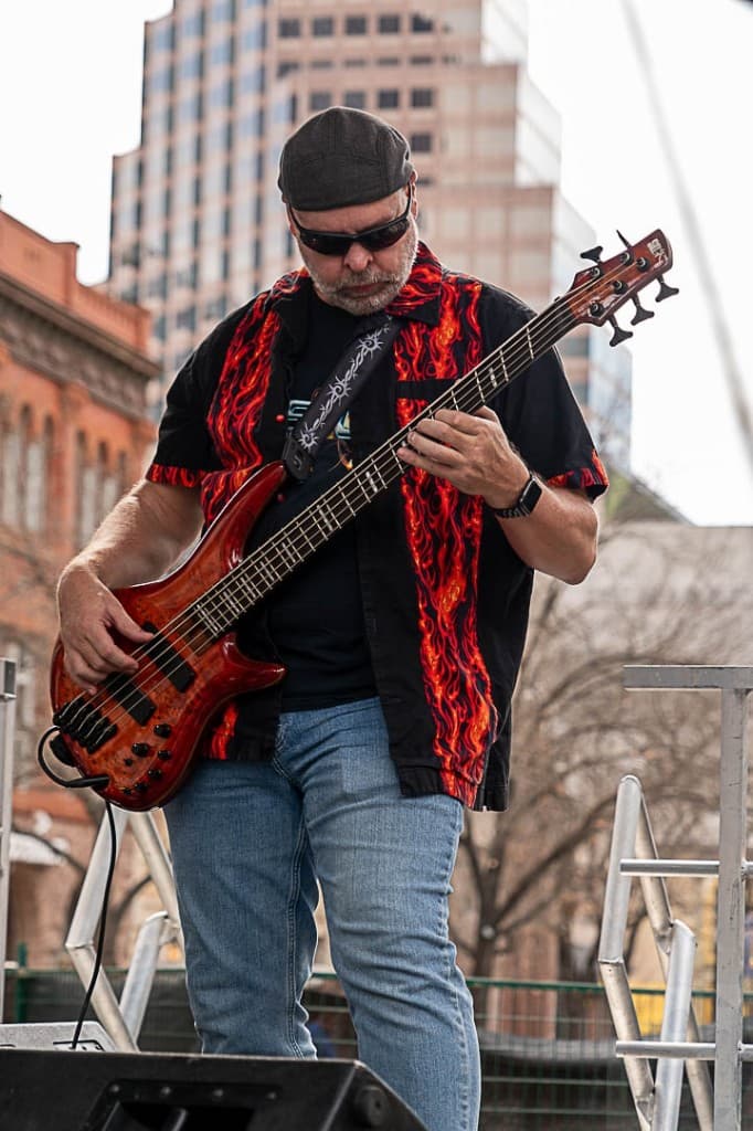 Close-up of bass guitar strings and hand movement.