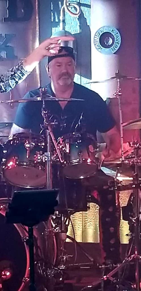 Drummer playing under bright stage lights.
